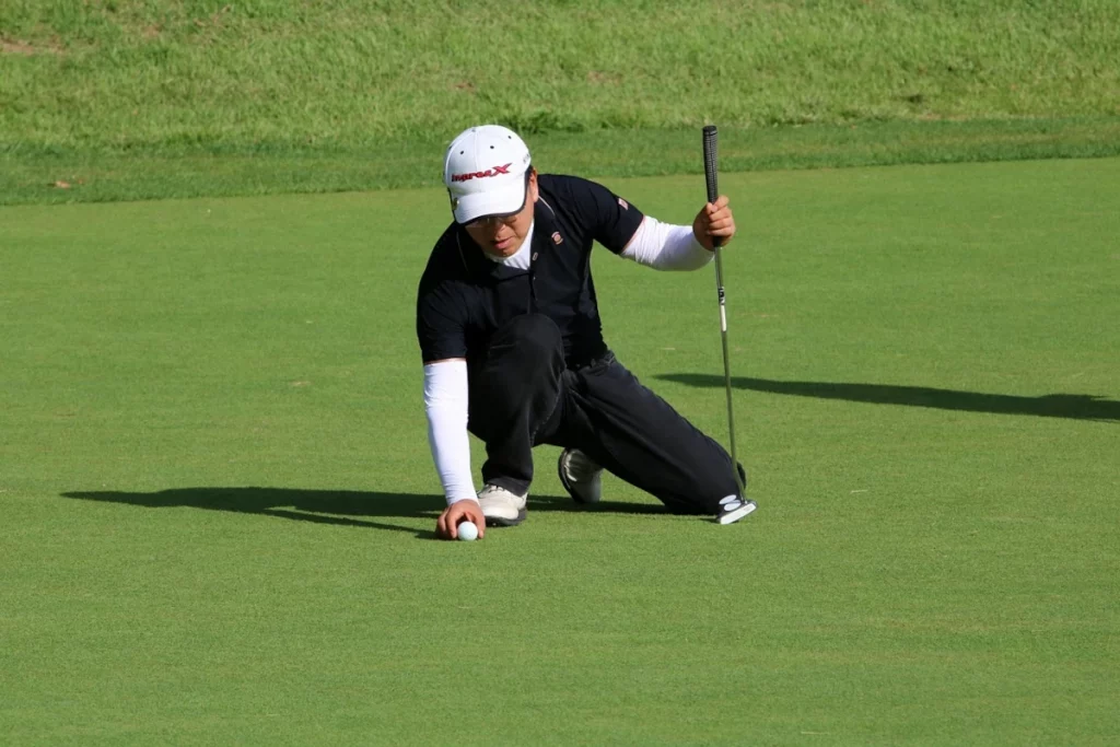Jugador de golf colocando la bola en el green con concentración antes de puttear