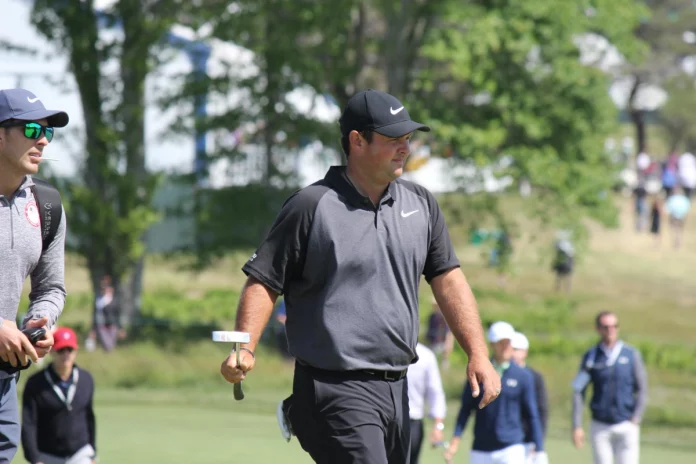 Patrick Reed con su caddie analizando su estrategia en el campo de golf.
