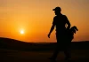 Silueta de un caddie cargando palos al atardecer en un campo de golf ondulado, símbolo del papel discreto pero vital en el golf profesional.
