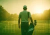 ¿Qué es el scoring average en golf? Golfista profesional caminando con gráficos de scoring average sobre el campo